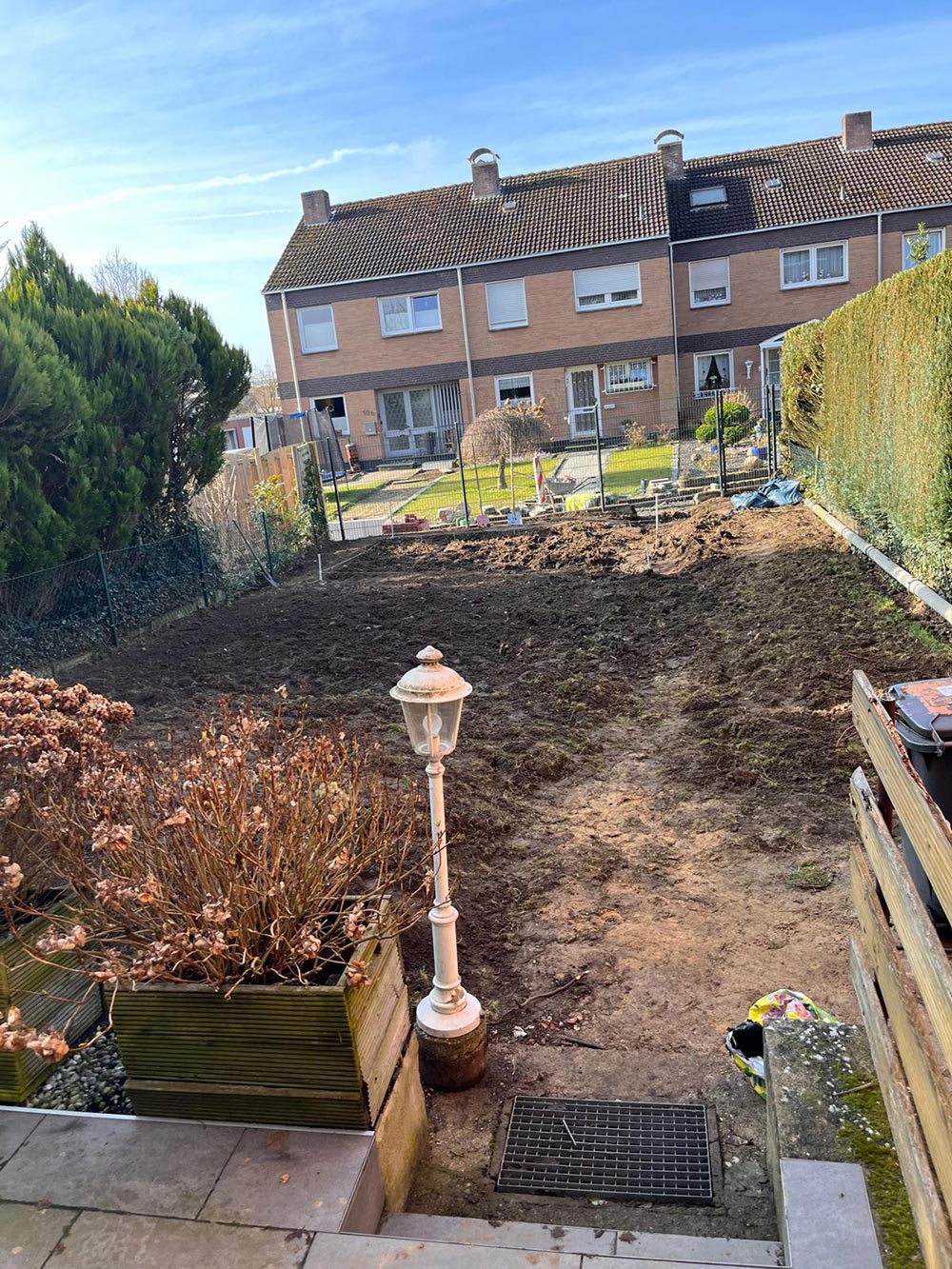Ein Garten mit frisch umgegrabener Erde, umgeben von Wohnhäusern und Hecken