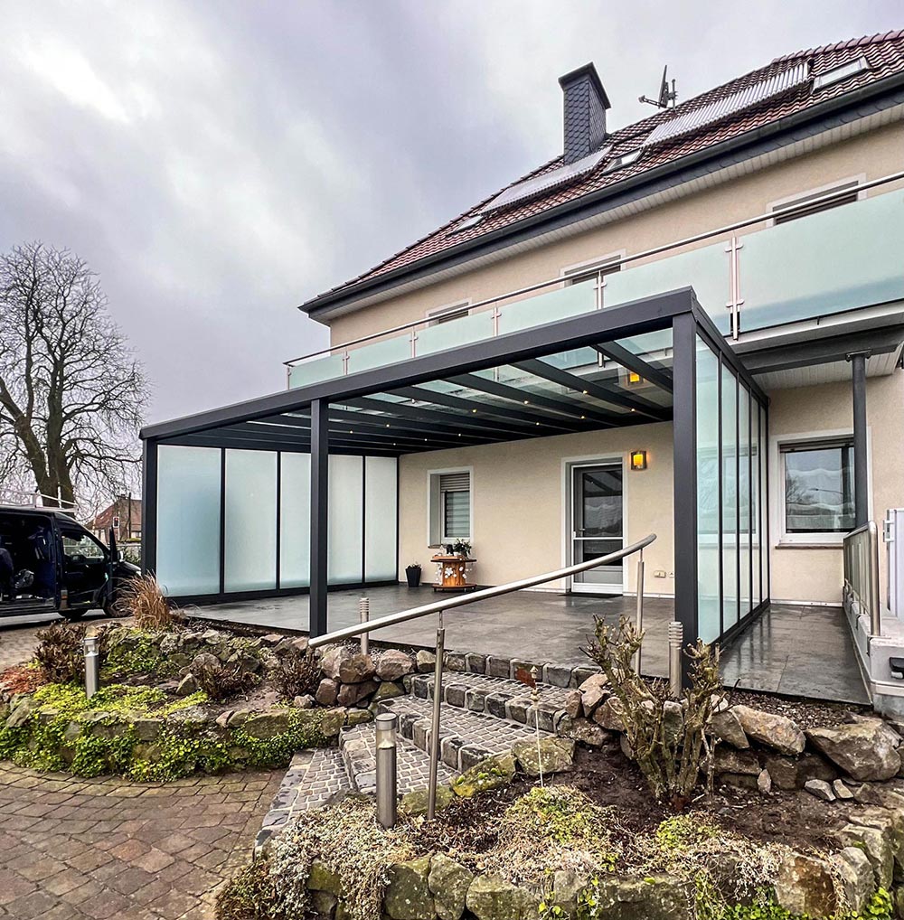 Ein modernes Haus mit Glasüberdachung und grauem Rahmen an einem bewölkten Tag